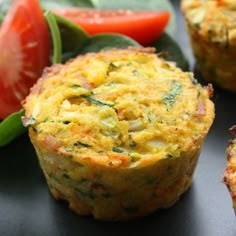 three muffins sitting on top of a table next to tomatoes