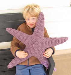 a young boy sitting on a bench holding a stuffed starfish