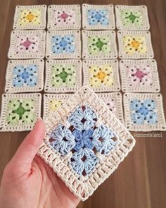 someone is holding up a crocheted square with small flowers on it and the squares are