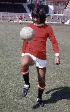 a young man kicking a soccer ball on top of a field