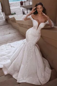 a woman in a white wedding dress leaning against a wall with her hand on her head