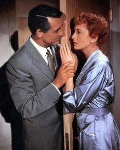 a man and woman standing next to each other in front of a door with their hands together