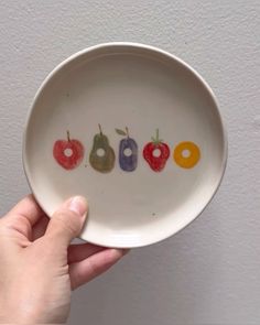 a person holding a white bowl with fruit on the bottom that says, ooh