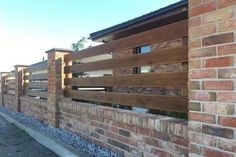 a brick wall with wooden slats on the top and bottom part, along side it