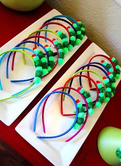 two white plates topped with green and red beaded bracelets next to an apple