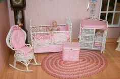 a doll house bedroom with pink furniture and accessories on the wooden floor, including a baby crib