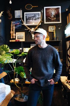 a man standing in front of a plant with antlers on the wall behind him