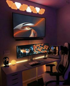 two computer monitors sitting on top of a desk in front of a flat screen tv