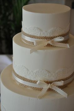 three tiered wedding cake with lace and bows