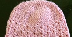 a pink crocheted hat with a white heart on it's front end