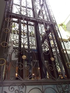 an iron gate with flowers on it in front of a building's entrance door