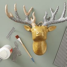 a gold deer head on the wall next to some other items and paintbrushes