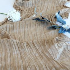 two blue and white flowers laying on top of a piece of cloth covered in wax paper