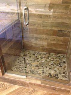 a walk in shower sitting next to a wooden floor