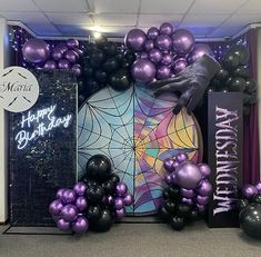 purple and black balloons are on display in front of the entrance to a birthday party