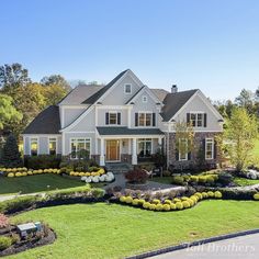 a large white house with lots of landscaping on the front lawn and side yard area