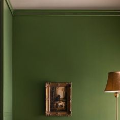 a living room with green walls and a painting on the wall next to a couch