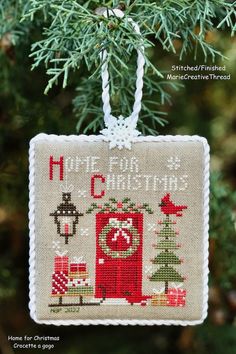 a cross stitch ornament hanging from a tree with the words home for christmas on it