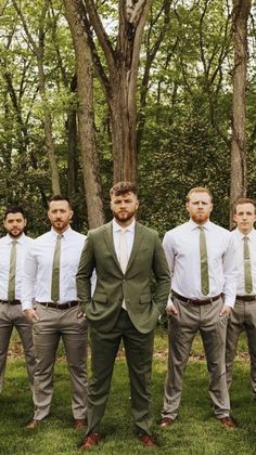 a group of men standing next to each other in front of trees with ties on