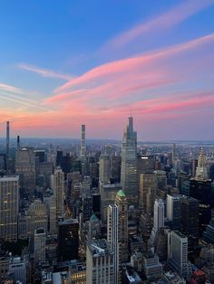 an aerial view of the city at sunset with pink and blue clouds in the sky