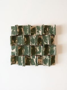 a green and white tile wall hanging on the side of a wall in front of a white wall