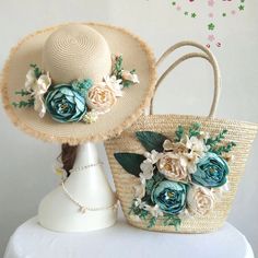 two straw hats with flowers on them are sitting next to each other in front of a white hat stand