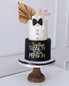 a three tiered black and white cake with gold decorations on it's top