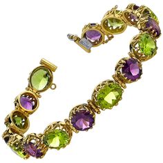 This exquisite 18k yellow gold tennis bracelet features over 33 carats of amethyst and peridot in luscious jewel-toned grape colors! Each round amethyst and oval peridot is showcased in its own gorgeous 18k yellow gold setting that is as beautiful from the side view as well as from the top. The scalloped basket design showcases both the fine gemstones and the artisan skill used to create this unique piece of jewelry. The clasp includes a safety chain for added security. Such a vibrant bracelet, full of life! Imagine yourself in a warm, sunny vineyard, sipping a glass of sparkling wine, wearing this exquisite, sparkling bracelet! Salut! Bracelet measures 7.50 inches in length Amethysts, 8.00mm, 12.60 carat total Peridots, 10.00 x 8.00mm, 21.05 carat total Amethyst And Peridot, Peridot Bracelet, Sparkle Bracelet, 18k Gold Bracelet, Peridot Jewelry, Antique Bracelets, Purple Jewelry, Handcrafted Bracelets, Amethyst Jewelry