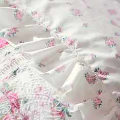 a white and pink bed spread with flowers on it