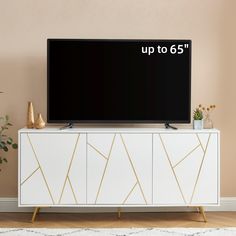 the tv is up to 65 inches tall and has gold lines on it, along with a plant