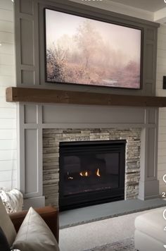 a living room with a fire place and television on the wall above it's fireplace