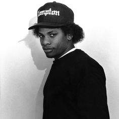 a young man wearing a hat standing in front of a wall