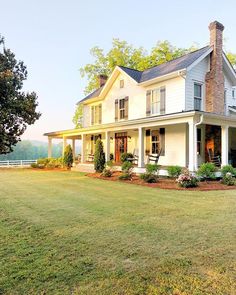 a large white house sitting on top of a lush green field