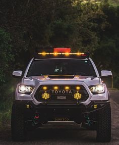 a toyota truck with its lights on driving down the road