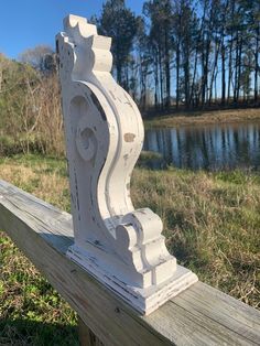 a wooden fence with an ornate design on the top and bottom, sitting in front of a body of water