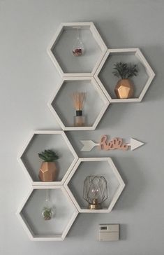 hexagonal shelves with plants, candles and other items on them are mounted to the wall