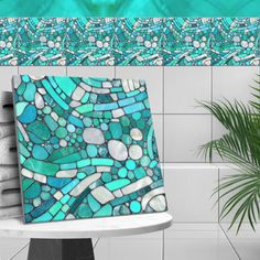 a blue and green mosaic tile design on a wall next to a potted plant