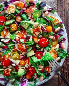 a white plate topped with salad next to a fork