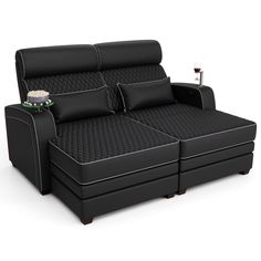 a black leather couch with two pillows and a wine glass on the armrests