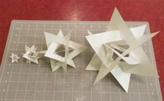 two white origami stars sitting on top of a cutting board