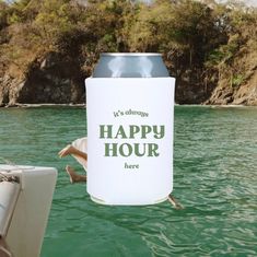 a can that is floating in the water next to a boat with a sign saying it's always happy hour here