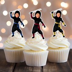 three cupcakes with cutouts of people in ninja suits on top of them