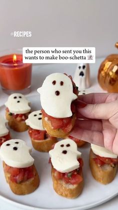 a person is holding up some food on a white plate with candles in the background