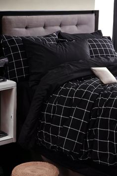 a bed with black and white comforter in a bedroom next to a night stand