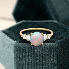 an opal and diamond ring sits in a velvet box