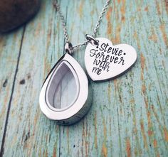 This teardrop urn necklace can be filled with your loved one's ashes so you can carry them with you wherever you go. The necklace is made of glass and stainless steel. It is hypoallergenicand will never tarnish. The pendant measures 1.25" and the chain is 18". I have also added a personalized 1" heart pendant. The name can be up to 7 characters long. The wording can be changed*. *I can fit up to 4 lines on the heart. Lines 1-3 can be up to 7 letters and line 4 can be up to 5 letters.*Please leav Teardrop Locket Necklace For Keepsake, Teardrop Locket Necklace Keepsake, Teardrop Necklace For Mother's Day, Personalized Teardrop Memorial Necklace, Personalized Teardrop Necklace For Memorial, Personalized Teardrop Pendant Necklace For Keepsake, Stainless Steel Teardrop Necklace For Gift, Cremation Necklaces, Urn Jewelry