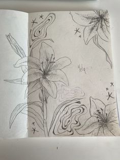 an open sketchbook with flowers and stars on the page, which has been drawn in pencil