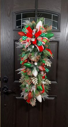 a christmas wreath hanging on the front door decorated with candy canes and bows,