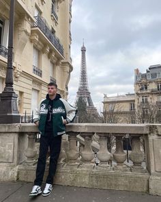 a man is standing on a balcony in front of the eiffel tower