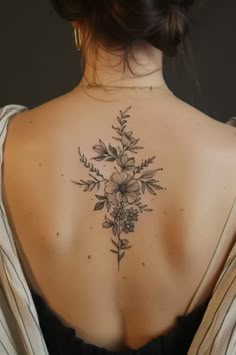 a woman's back tattoo with flowers and leaves on her left upper back shoulder